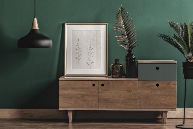 Bild mit einem Sideboard, Dekorationen und einer grünen Wand